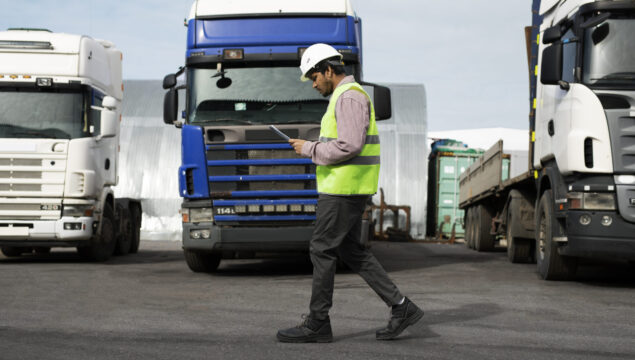 full-shot-man-walking-by-trucks-fleet