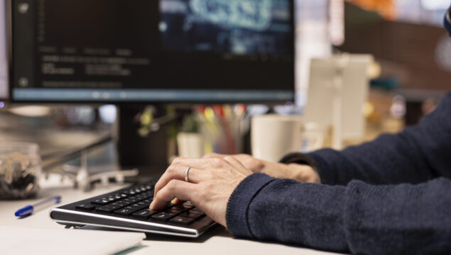 Startup programmer leveraging artificial intelligence tech in office to gain competitive edge. Close up of AI specialist typing on PC keyboard, working on rapid technological advancement