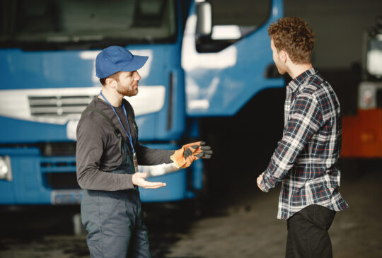 Two guys talking about work. Work in garage near truck. Transfer of documents with goods