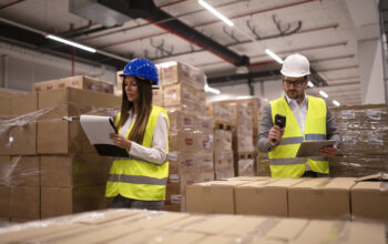 Warehouse workers using bar code scanner and tablet and checking goods inventory.